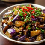 Serving of Chinese eggplant in garlic sauce garnished with herbs and spices