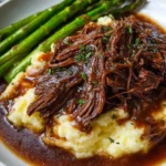 Crockpot shredded beef served with rich gravy on a plate