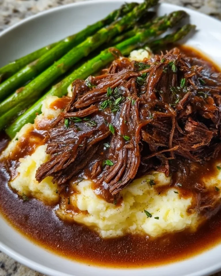 Crockpot shredded beef served with rich gravy on a plate