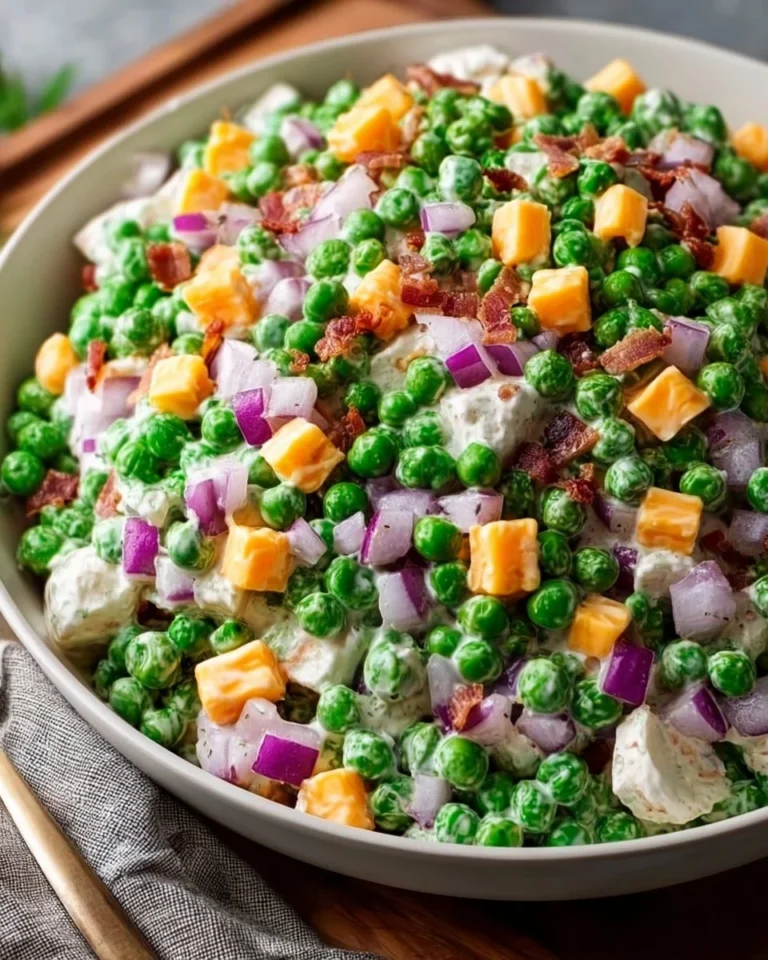 A bowl of classic pea salad with fresh peas, onions, and creamy dressing.
