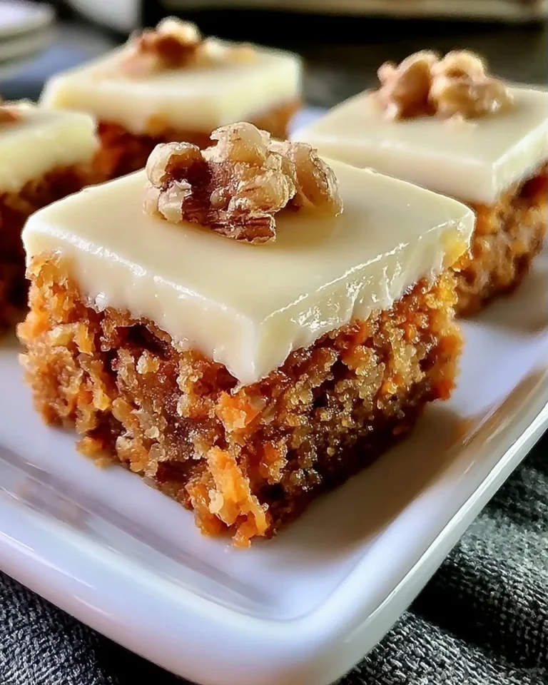 Delicious carrot cake bars topped with creamy frosting on a plate