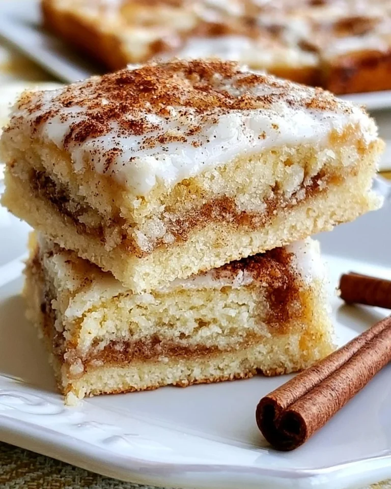 Delicious cinnamon roll dessert bars drizzled with icing on a white plate.