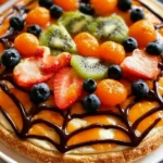 Halloween Fruit Pizza decorated with spooky fruit toppings for a festive treat.